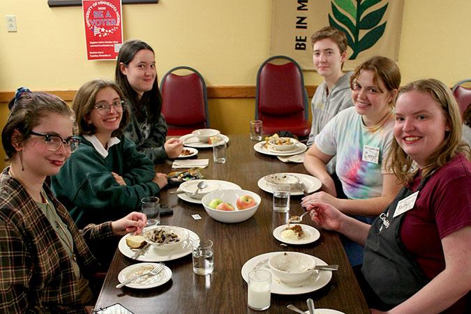 Several student leaders enjoy the food at a community meal after serving others.