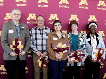 Five UMN Morris employees standing in front of a maroon and gold backdrop